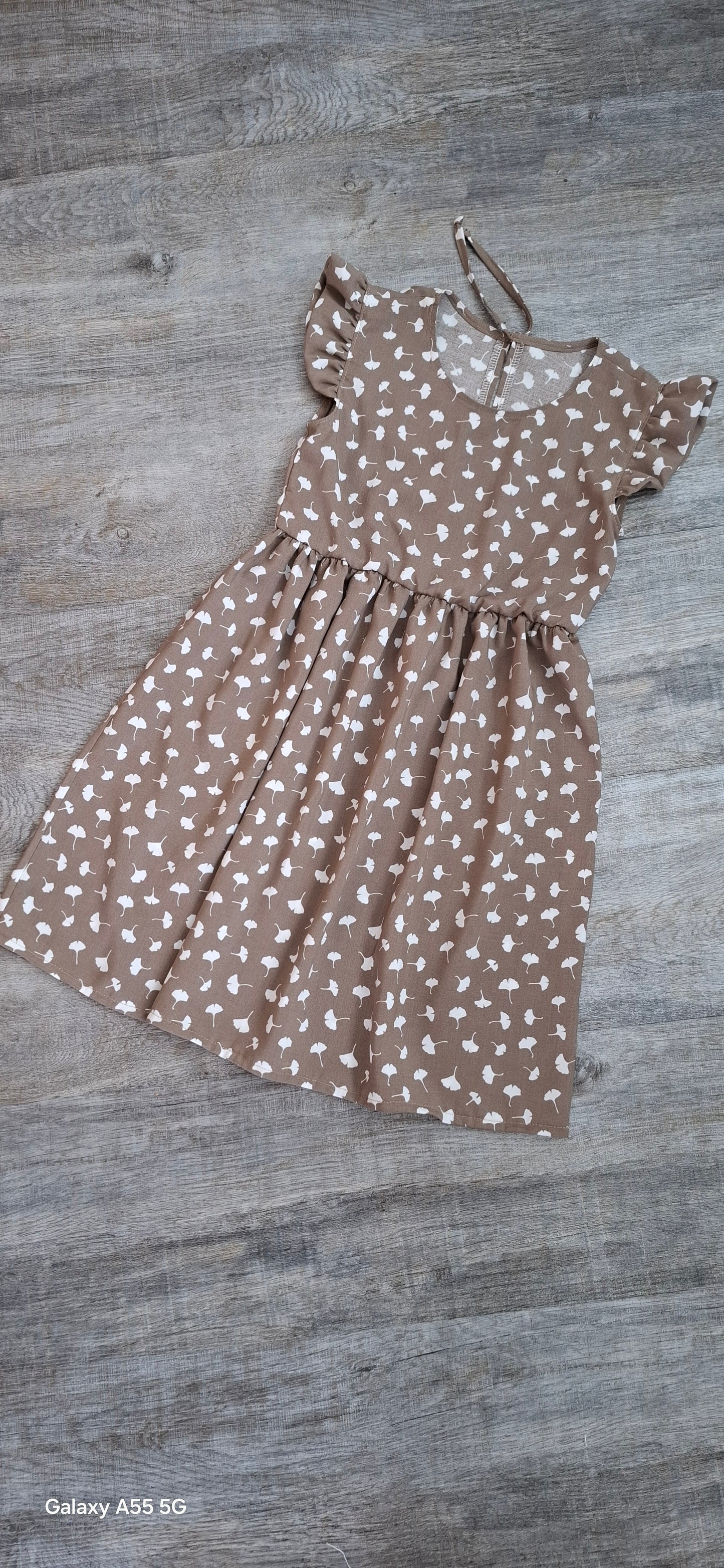 Mädchen Sommerkleid aus Bambus-Popeline in Taupe mit weißen Pusteblumen – Flügelärmel – nachhaltige Kinderkleidung.