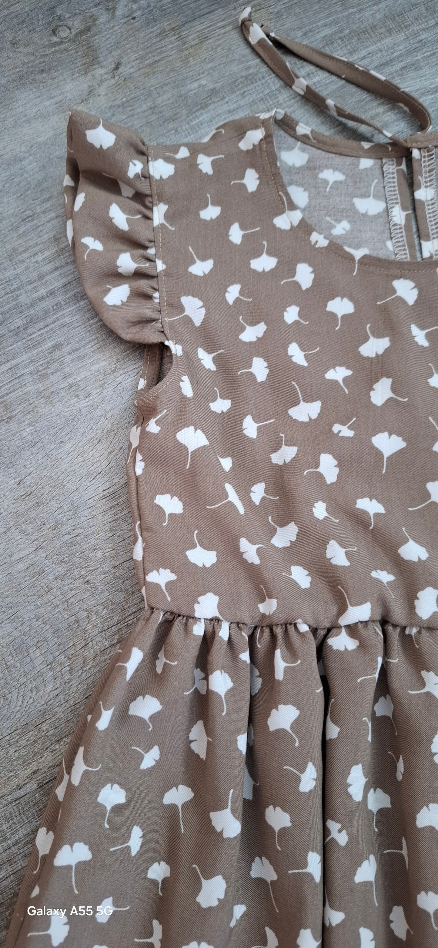Mädchen Sommerkleid aus Bambus-Popeline in Taupe mit weißen Pusteblumen – Flügelärmel – nachhaltige Kinderkleidung.