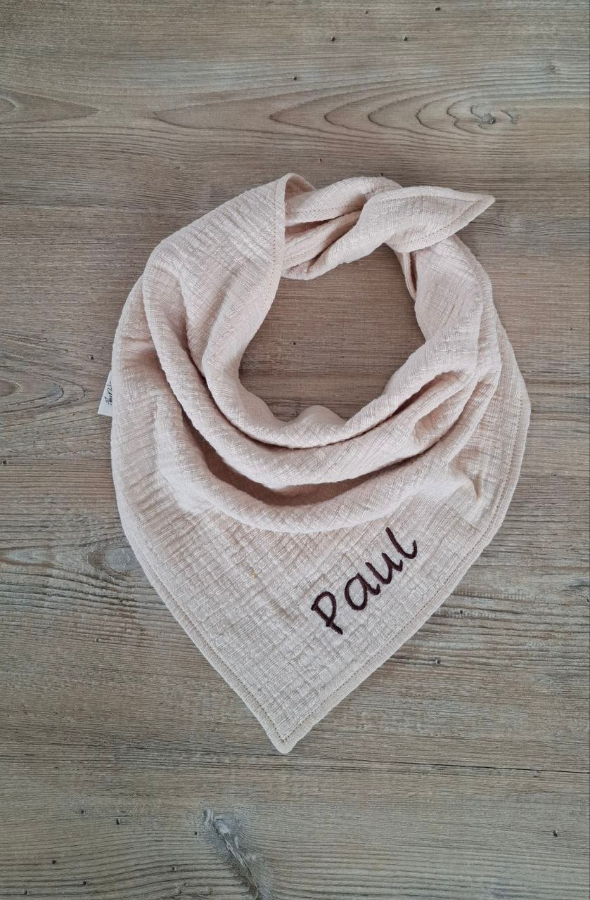 Personalisiertes Musselin-Halstuch in Rosa mit dem Namen Paul auf Holzgrund.